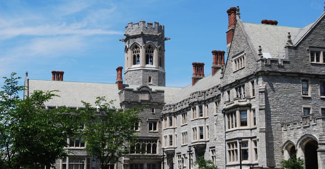 Das historische Schulgebäude aus Stein der Emma Willard School mit einem Turm und Schornsteinen unter blauem Himmel.