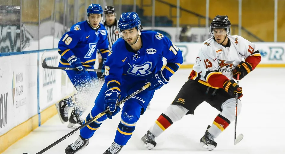Studenti della Sir Wilfrid Laurier Secondary School giocano una partita di hockey sulla pista da ghiaccio con spettatori sullo sfondo.