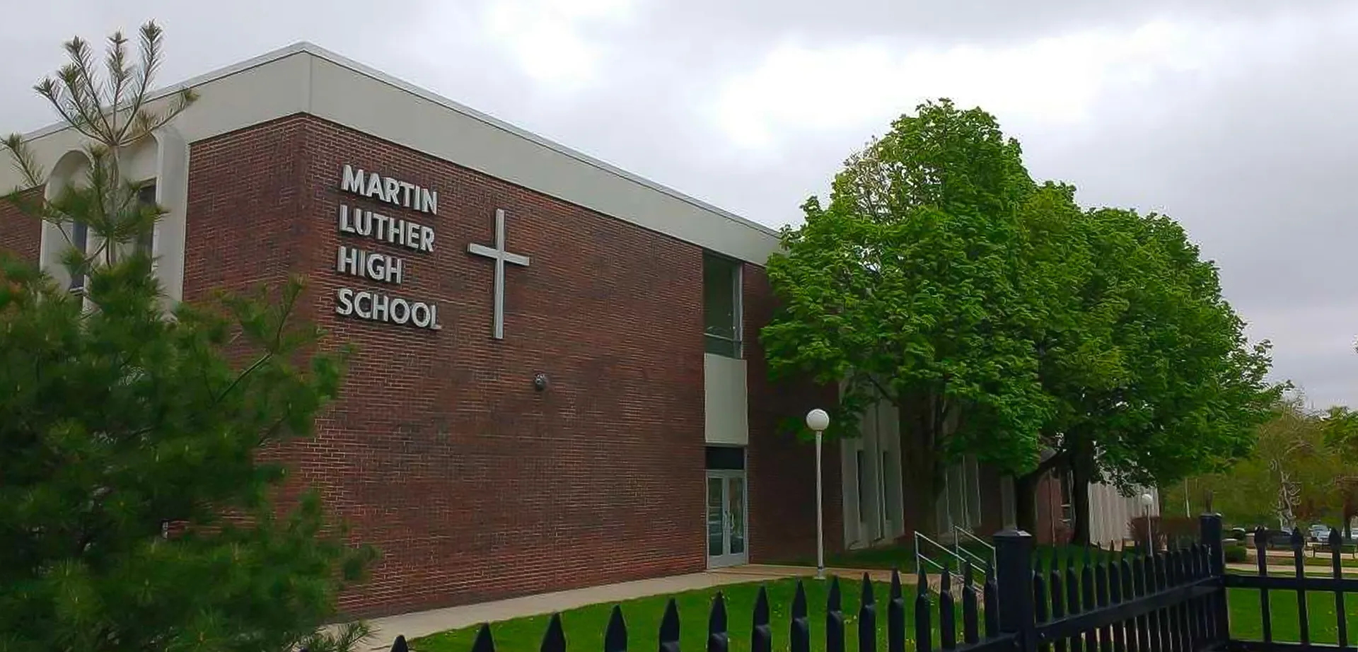 L'edificio in mattoni della Martin Luther High School è circondato da alberi verdi.