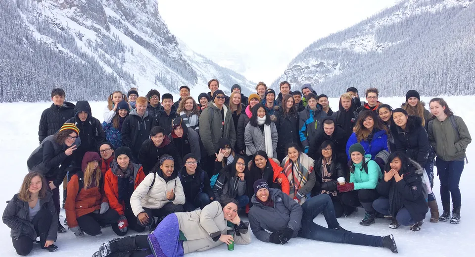Studenti e studentesse della Sir Charles Tupper Secondary School si radunano in un paesaggio montano innevato con cime innevate sullo sfondo.