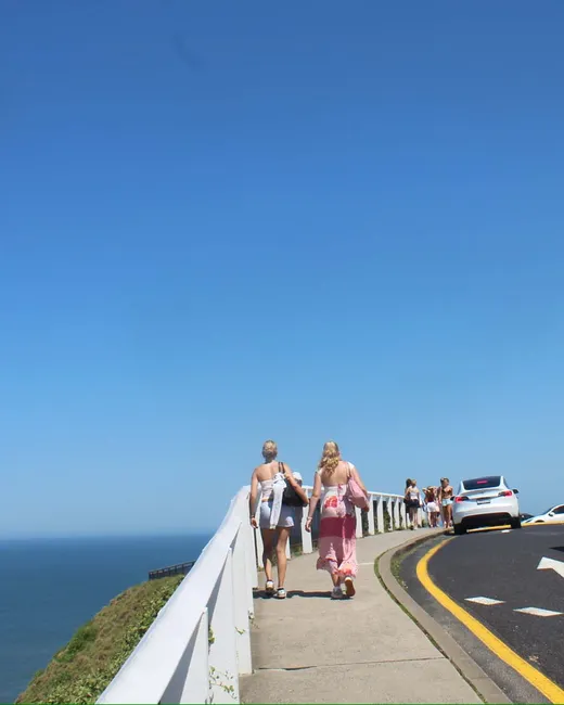 Dos chicas caminan por un sendero costero junto al mar