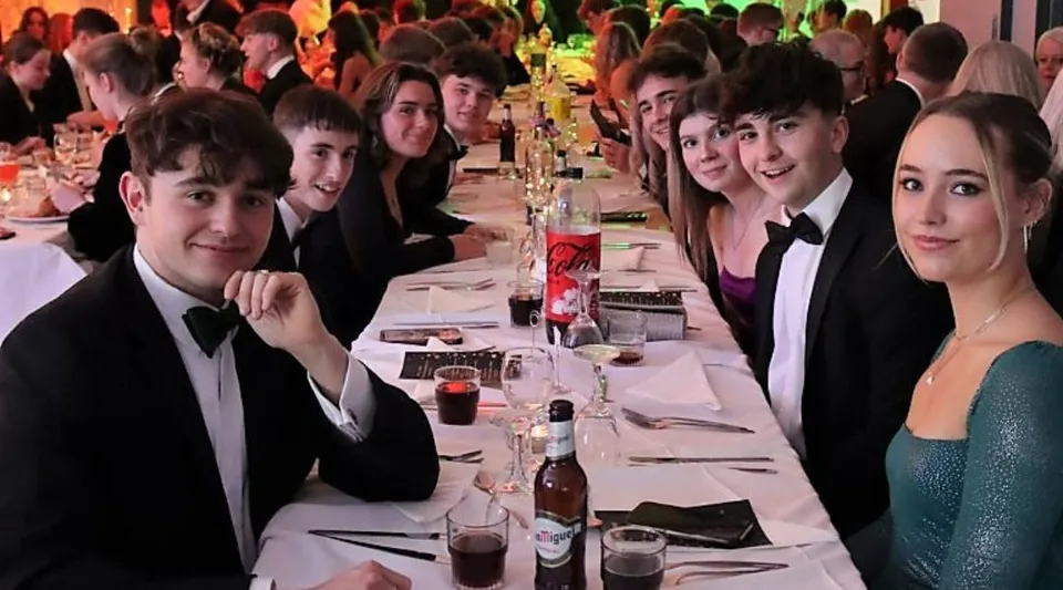 Studenti della Austin Friars School durante una cena formale a un lungo tavolo.
