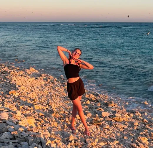 Antonia posiert an einem steinigen Strand vor dem türkisen Meer in Australien
