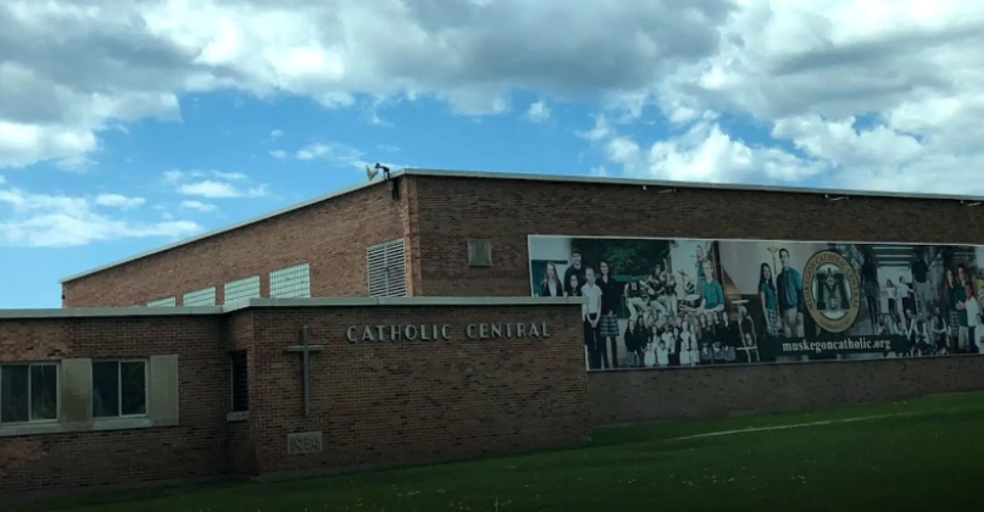 L'edificio in mattoni della Muskegon Catholic Central High School davanti a un cielo blu nuvoloso.