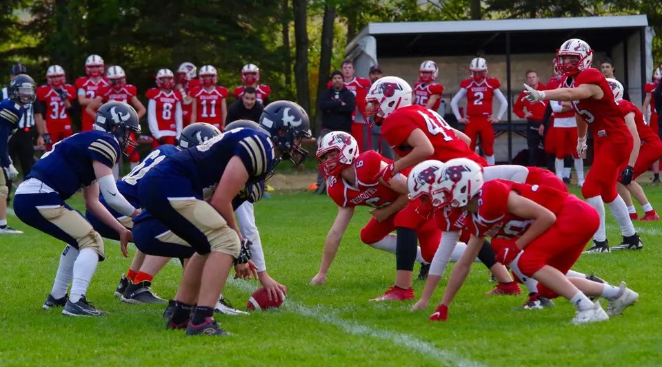 Studenti del Collège de Sainte-Anne-de-la-Pocatière giocano una partita di calcio sul campo sportivo con alberi sullo sfondo.