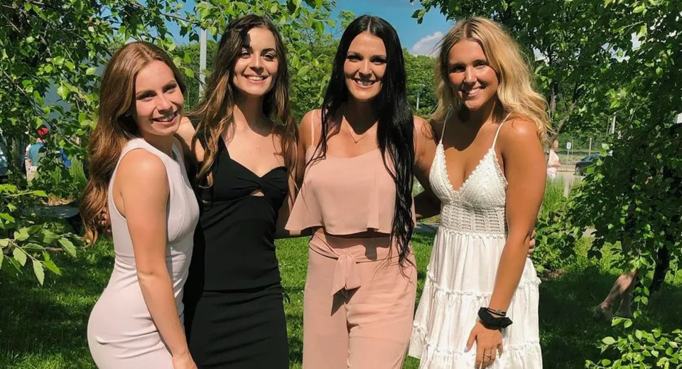 Quattro studentesse sono in piedi nell'area verde esterna nel campus della Nantyr Shores Secondary School.