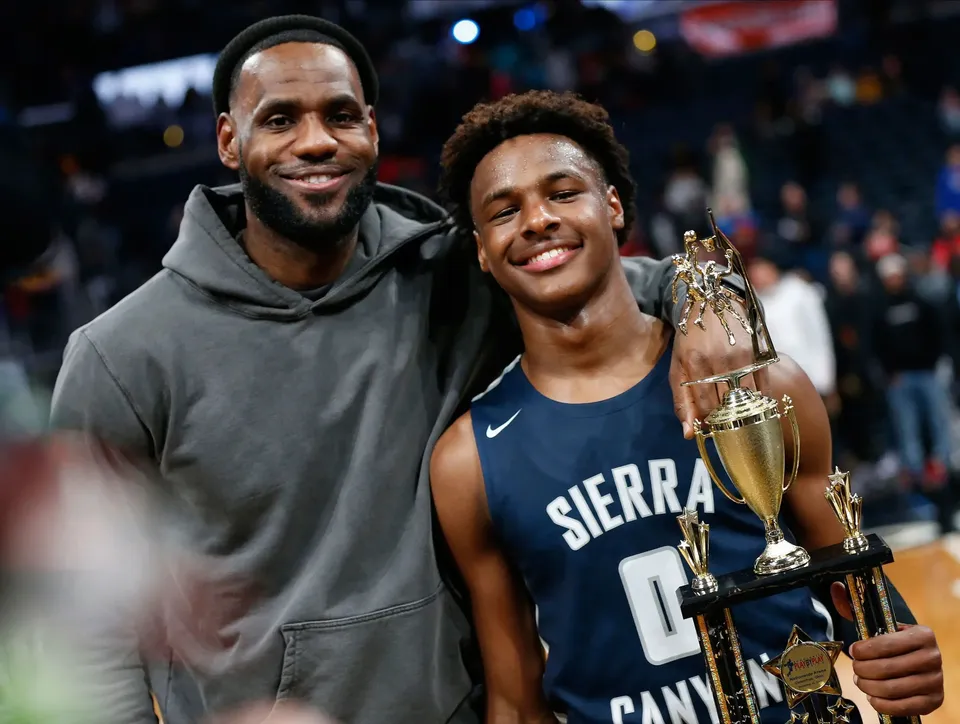 LeBron James accanto a un giocatore di pallacanestro della Sierra Canyon School che sorride e tiene un trofeo.