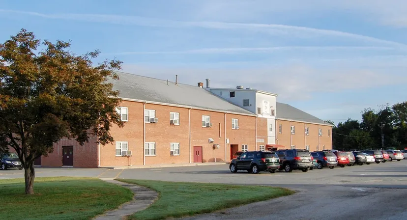 L'edificio in mattoni della Tri-State Christian School è circondato da alberi e da un'area verde con un parcheggio in primo piano.