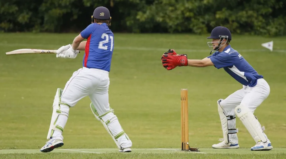 Due giocatori di cricket in uniforme blu disputano una partita sul campo del Rosmini College.