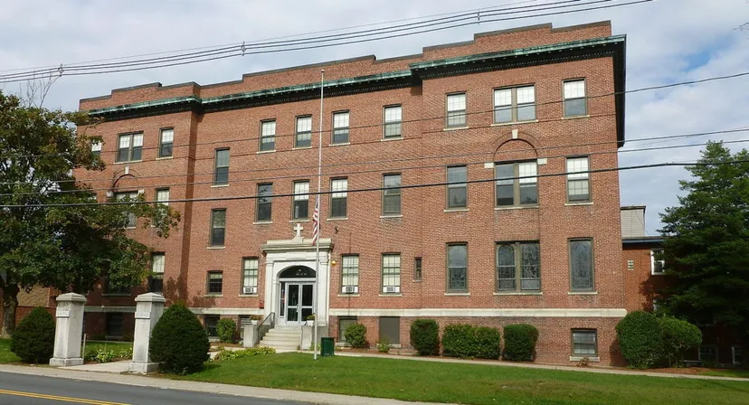 L'edificio in mattoni a più piani con un magnifico ingresso sul campus della Lowell Catholic High School è circondato da un'area verde curata.