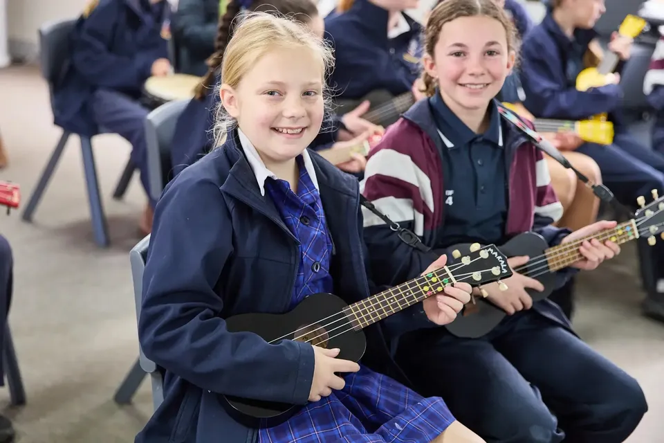 Due studentesse della Cobram Anglican Grammar School sono sedute con gli ukulele in un'aula.