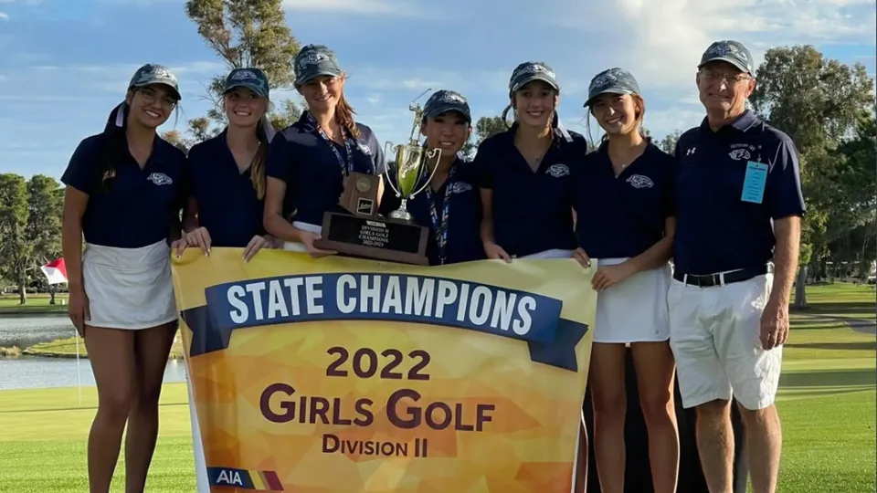 Un gruppo di studentesse della Cactus Shadows High School tiene un trofeo davanti a uno striscione delle State Champions 2022 nel golf femminile.