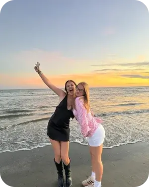 Helen e un'amica sorridono sulla spiaggia al tramonto negli Stati Uniti.