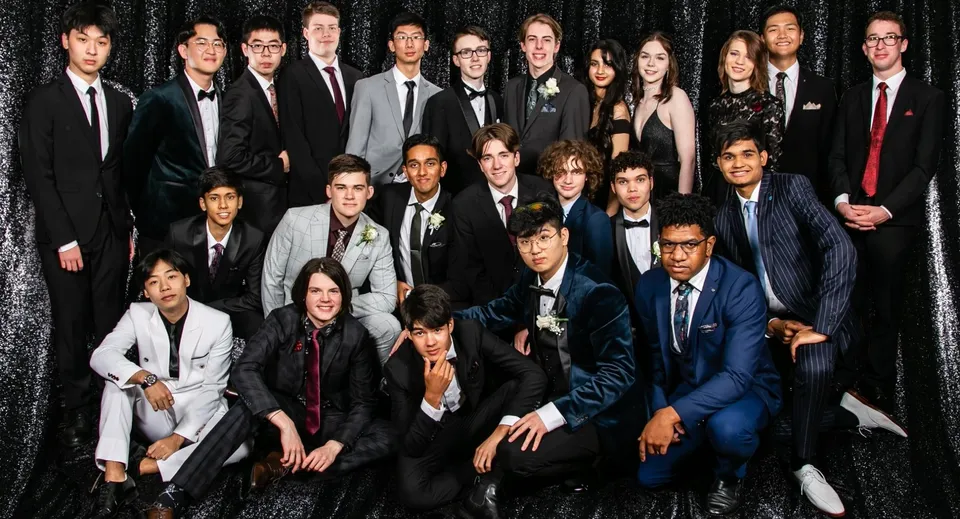 Un grande gruppo di studenti vestiti in modo formale posa per una foto di gruppo al John Paul College.