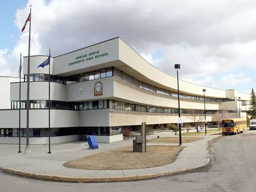 Das moderne mehrstöckige Gebäude der Spruce Grove Composite High School und kanadischer Flagge davor.