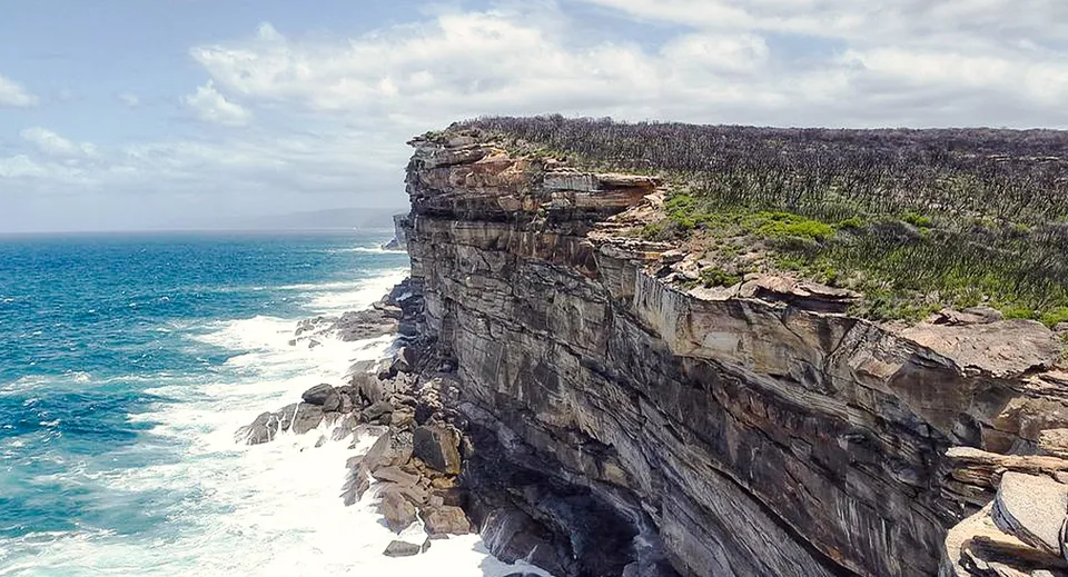 Un tratto di scogliera rocciosa con rigogliosa vegetazione si affaccia sul mare turchese nei pressi del Nambour State College.