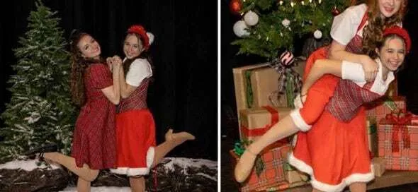 Dos chicas jóvenes vestidas de rojo posan sonrientes junto a un árbol de Navidad y regalos