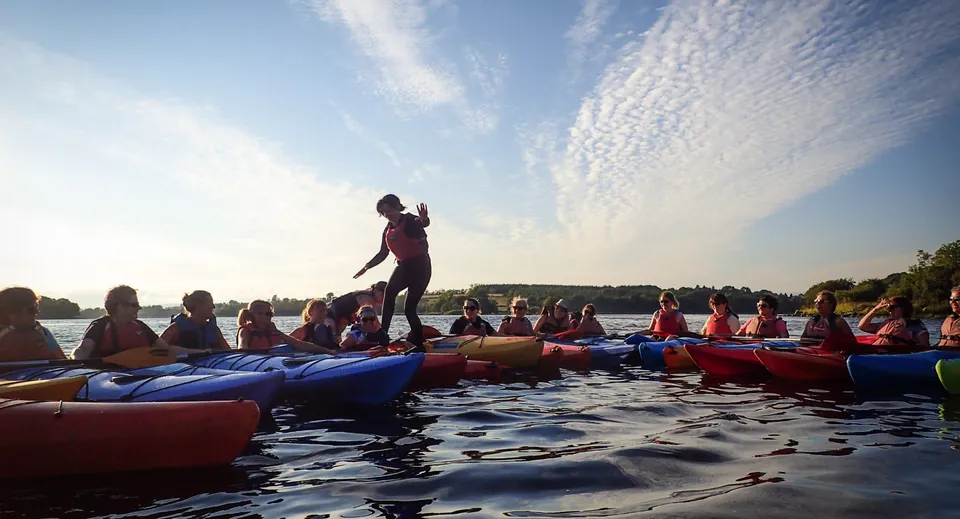Studenti della Bush Post Primary School che fanno rafting insieme su uno specchio d'acqua sotto un cielo nuvoloso.