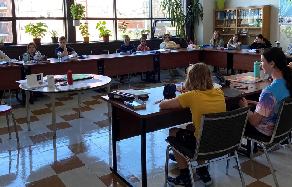 Un gruppo di studenti è seduto in un'aula luminosa della École secondaire publique L'Alternative con vista sull'esterno.