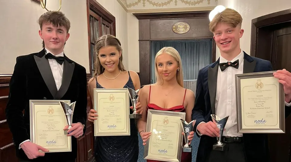 Quattro persone della Kirkham Grammar School tengono dei premi in una stanza dalle decorazioni sfarzose.