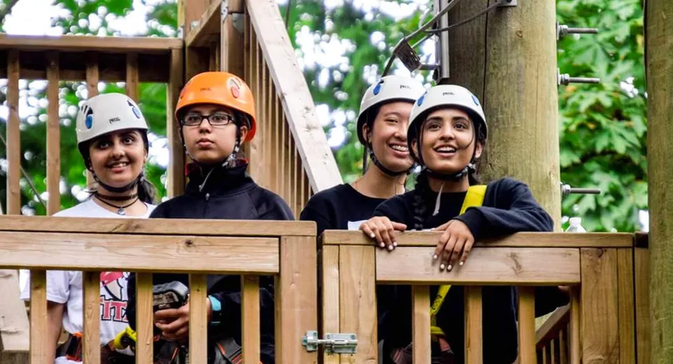 Studenti della Abbotsford Traditional Secondary School si trovano su una piattaforma di legno nel verde con elmetti protettivi e abbigliamento di sicurezza.