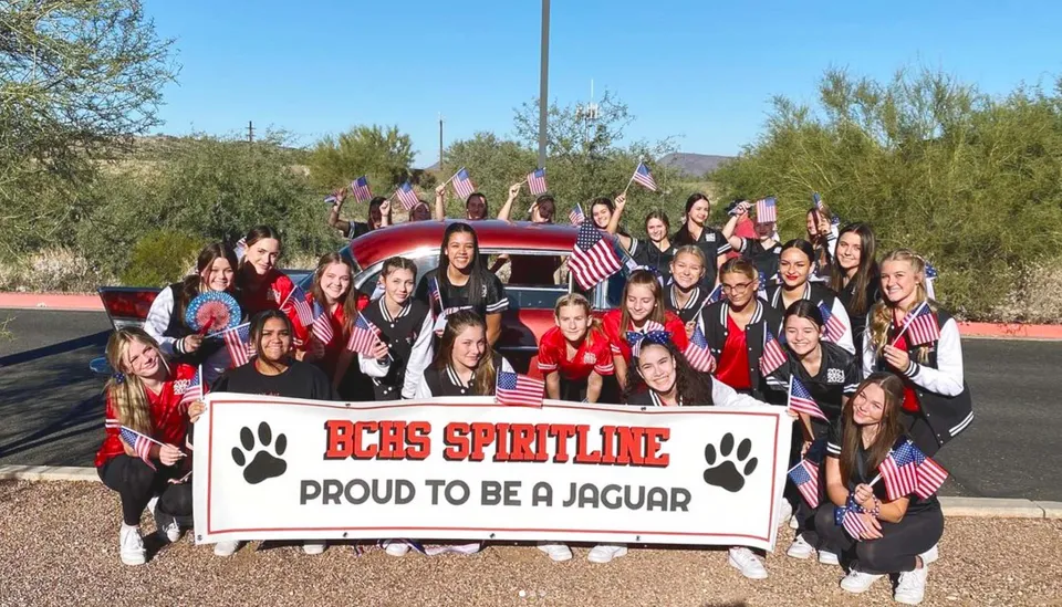 Un gruppo di studenti della Boulder Creek High School posa davanti a un veicolo rosso e a uno striscione della Spirit Line.