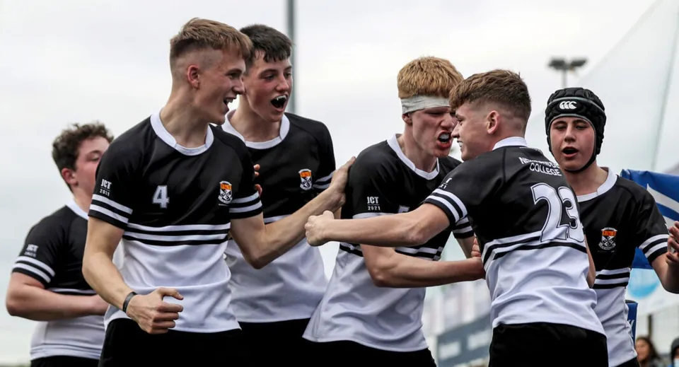 Un gruppo di studenti in tenuta sportiva festeggia insieme sul campo da gioco del Newbridge College.