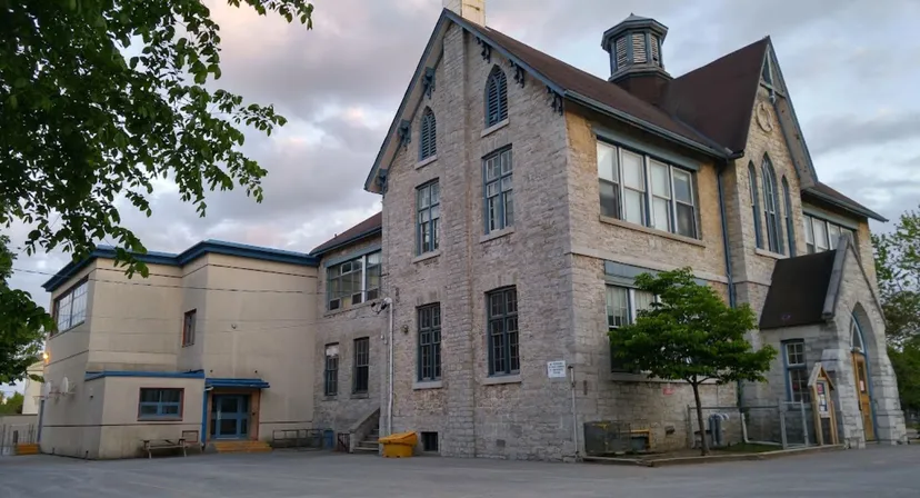 L'edificio in mattoni a più piani con una torre caratteristica appartiene alla Sydenham High School ed è circondato da alberi.