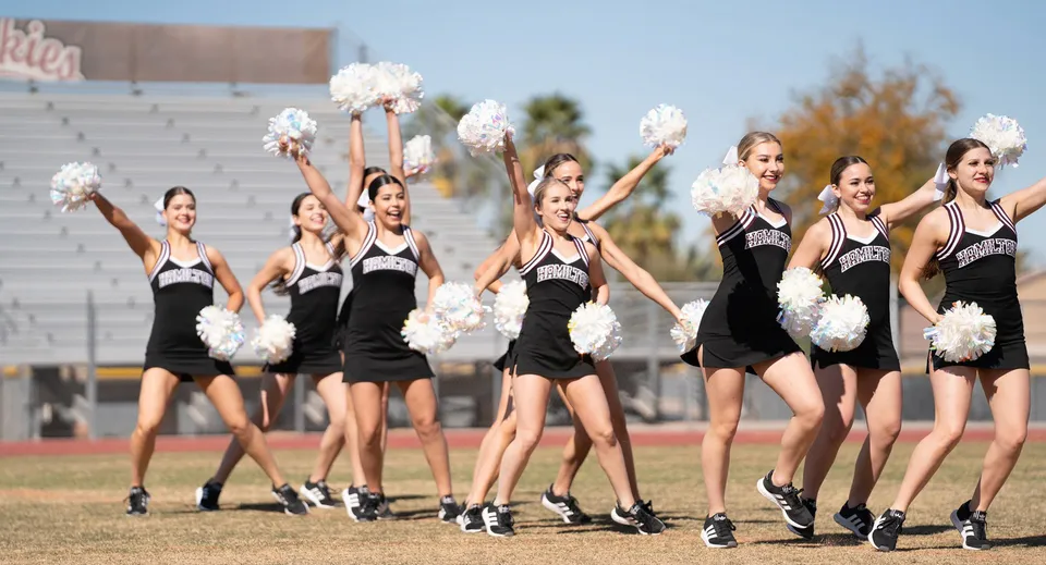 Un gruppo di cheerleader della Hamilton High School si esibisce sul campo sportivo davanti allo stadio.