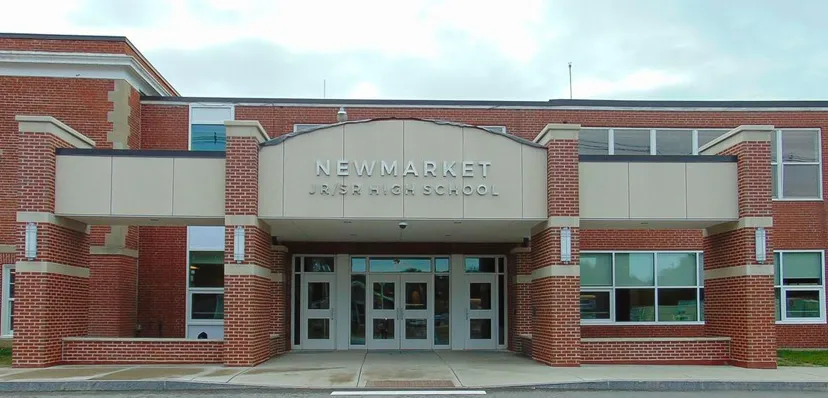 L'edificio in mattoni con l'ingresso principale della Newmarket High School sotto un cielo nuvoloso.