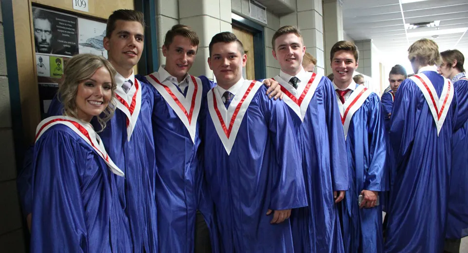 Studenti della Strathmore High School con la toga blu da diploma si trovano nel corridoio davanti a una lavagna.