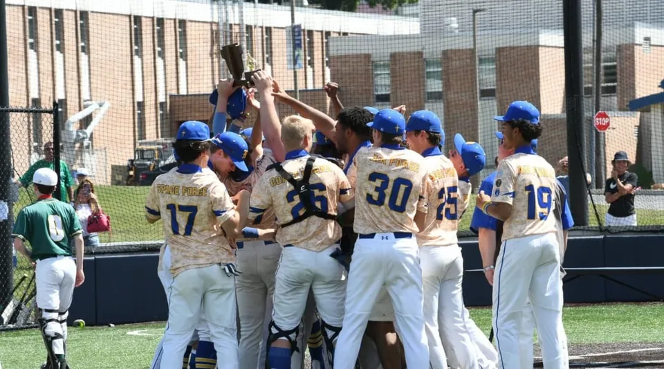 Un gruppo di studenti di baseball in divisa sul campo da gioco davanti all'edificio della Marian Catholic High School.