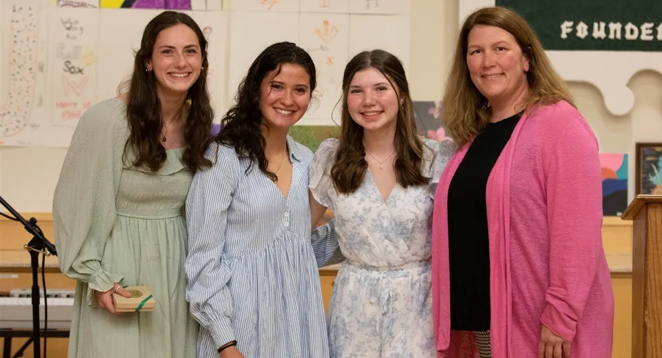 Quattro donne sorridono in piedi in un'aula della Winchendon School in Massachusetts.