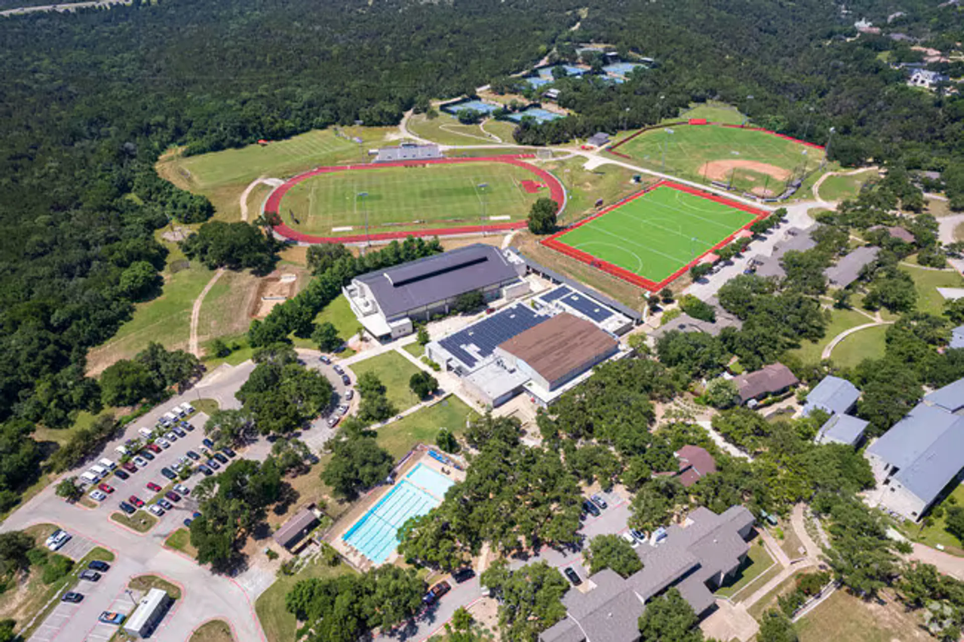 Vista aérea del campus de la St. Stephen's Episcopal School con pista de atletismo, campos deportivos, piscina y bosque alrededor.