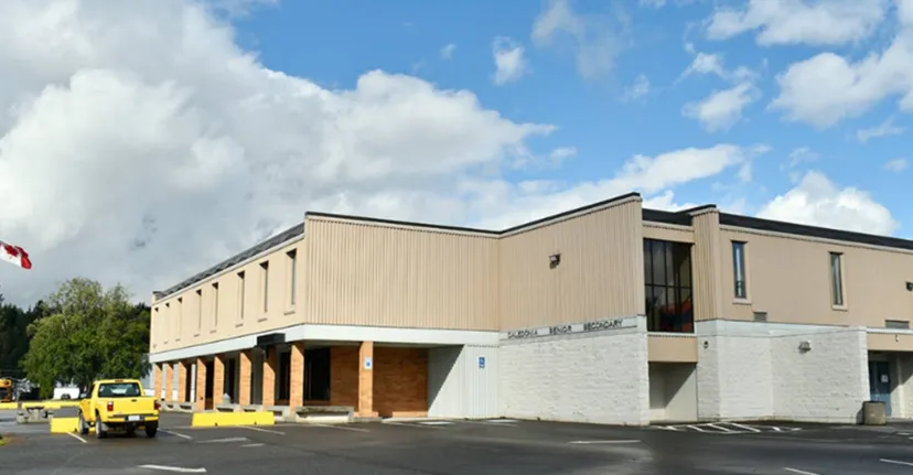L'edificio a due piani della Caledonia Secondary School con un parcheggio e un pickup giallo sul davanti.