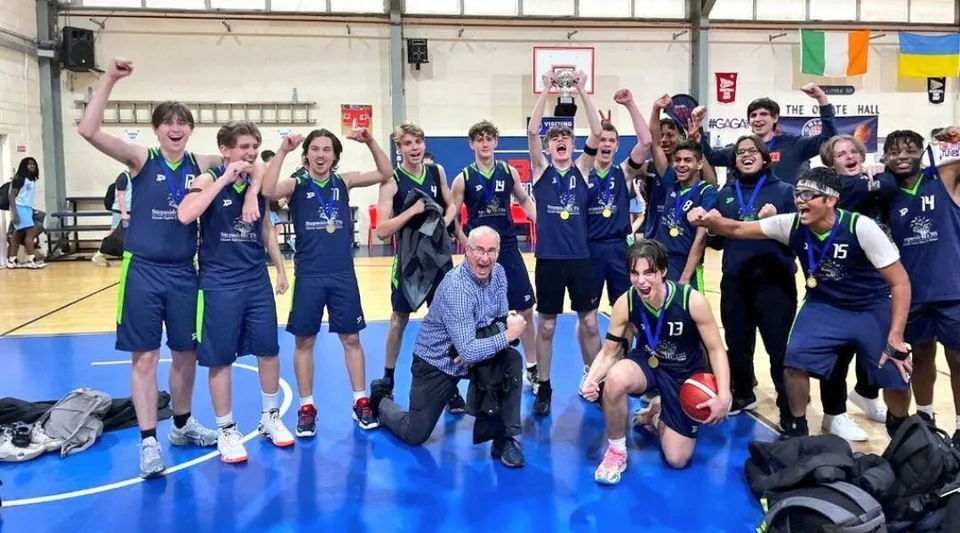 Un gruppo di studenti della Stepaside Educate Together Secondary School posa in palestra con attrezzi sportivi e striscioni sullo sfondo.