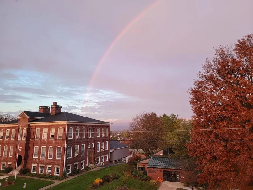 Backsteingebäude einer amerikanischen High School unter einem Regenbogen
