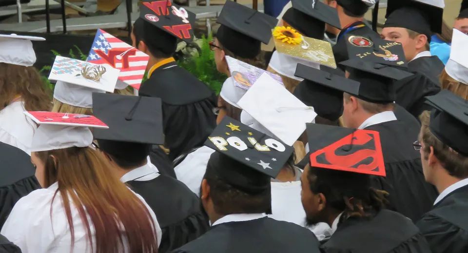 I diplomati del King William's College indossano toghe e tocchi neri durante una cerimonia di diploma all'aperto.