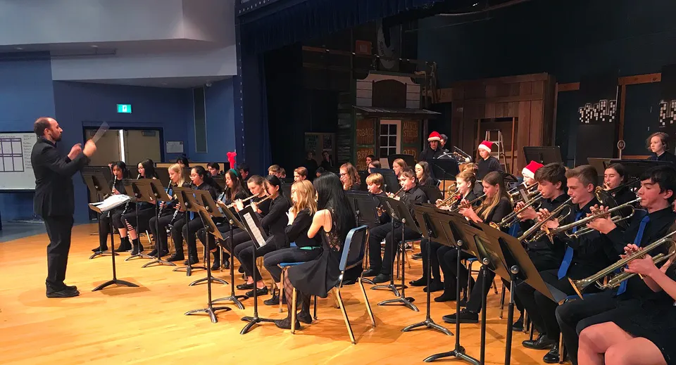 Un gruppo di studenti di musica della Parkland Secondary School suona sul palco sotto la direzione di un direttore d'orchestra.