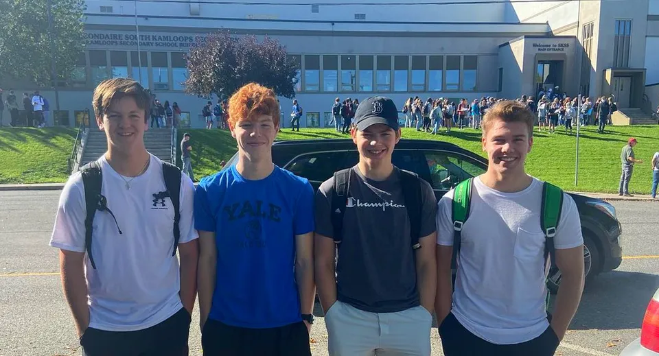 Quattro studenti sono insieme davanti a un grande edificio nel campus della South Kamloops Secondary School.