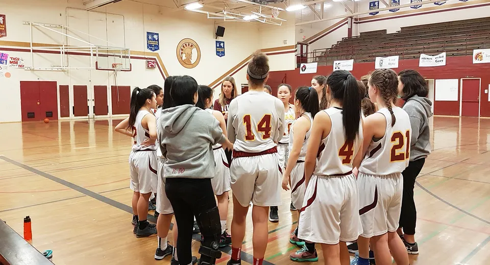 Un gruppo di giovani giocatori e giocatrici di basket si allena nella palestra della Templeton Secondary School.