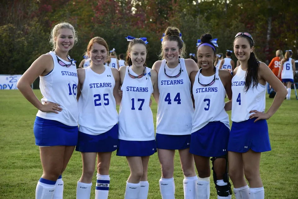 Sei studentesse in uniforme sportiva della Stearns High School insieme all'aperto davanti ad alberi e prati.
