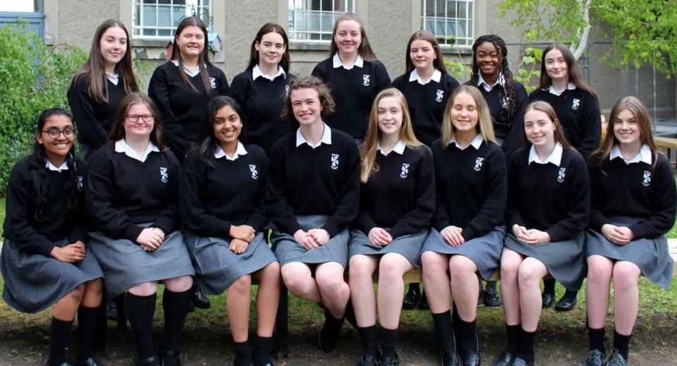 Un gruppo di studentesse del Dominican College Sion Hill si trova davanti a un edificio con grandi finestre.