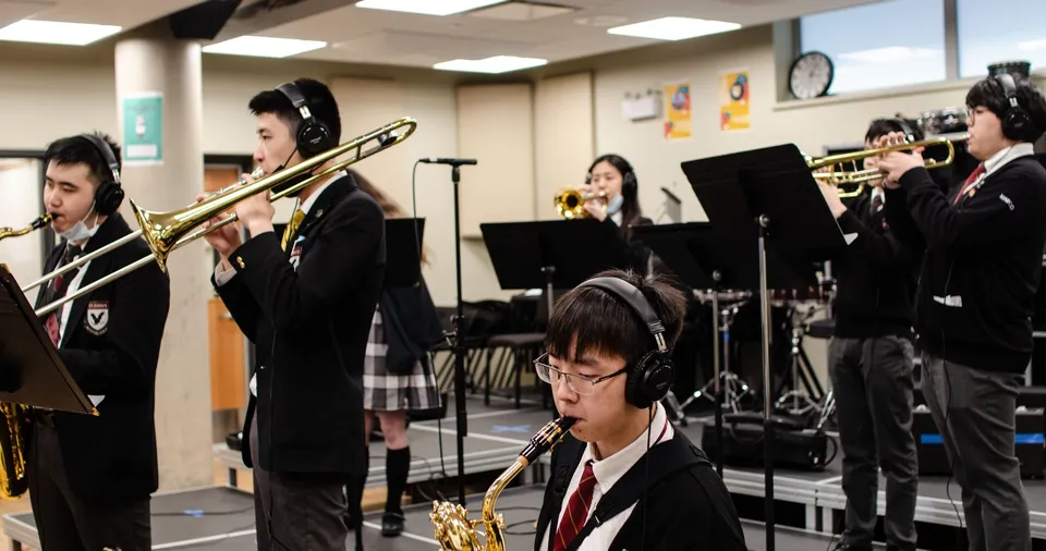 Gli studenti della Neufundland und Labrador suonano strumenti a fiato con le cuffie in un'aula di musica.