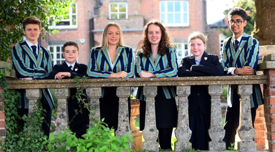 Studenti della Wisbech Grammar School si trovano su un ponte di legno circondati da una verde vegetazione.