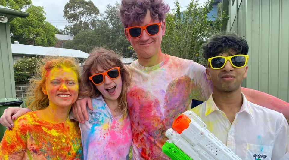 Studenti della Hunters Hill High School festeggiano insieme all'aperto circondati da una verde vegetazione.