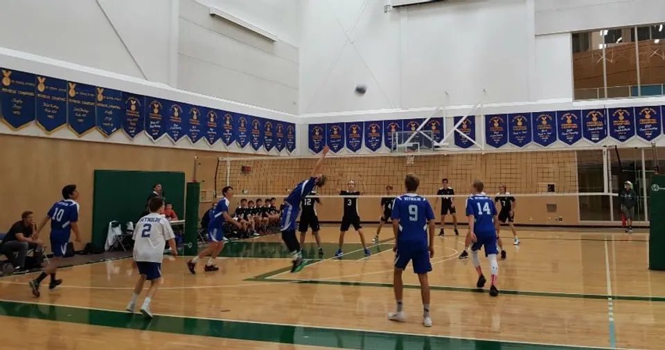 Studenti della Reynolds Secondary School giocano a basket su un campo da gioco con pavimento in legno e pareti bianche.