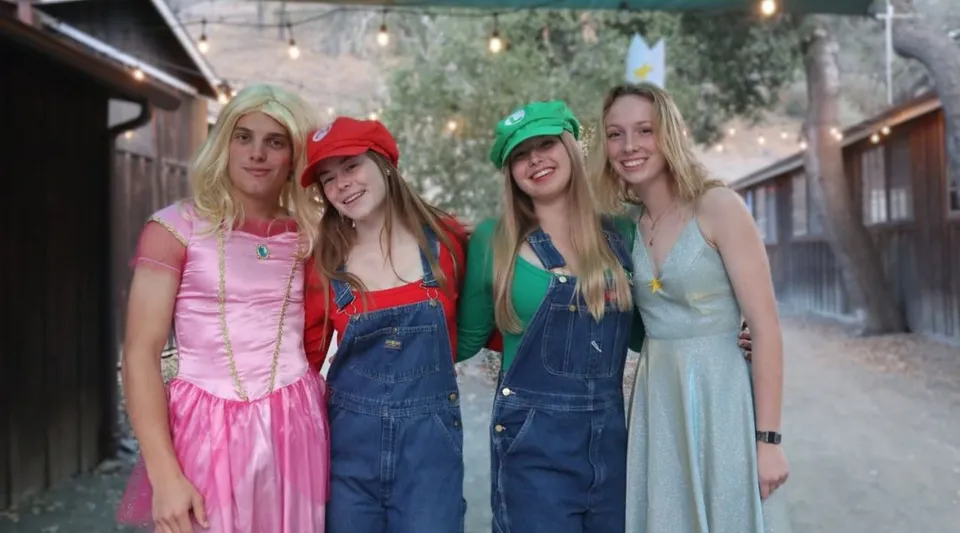 Quattro studentesse in costumi colorati sono insieme all'aperto nel campus della Midland School.