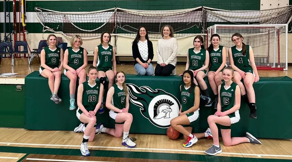 Un gruppo di giovani giocatrici di basket posa insieme sul campo da basket della Tofield School.