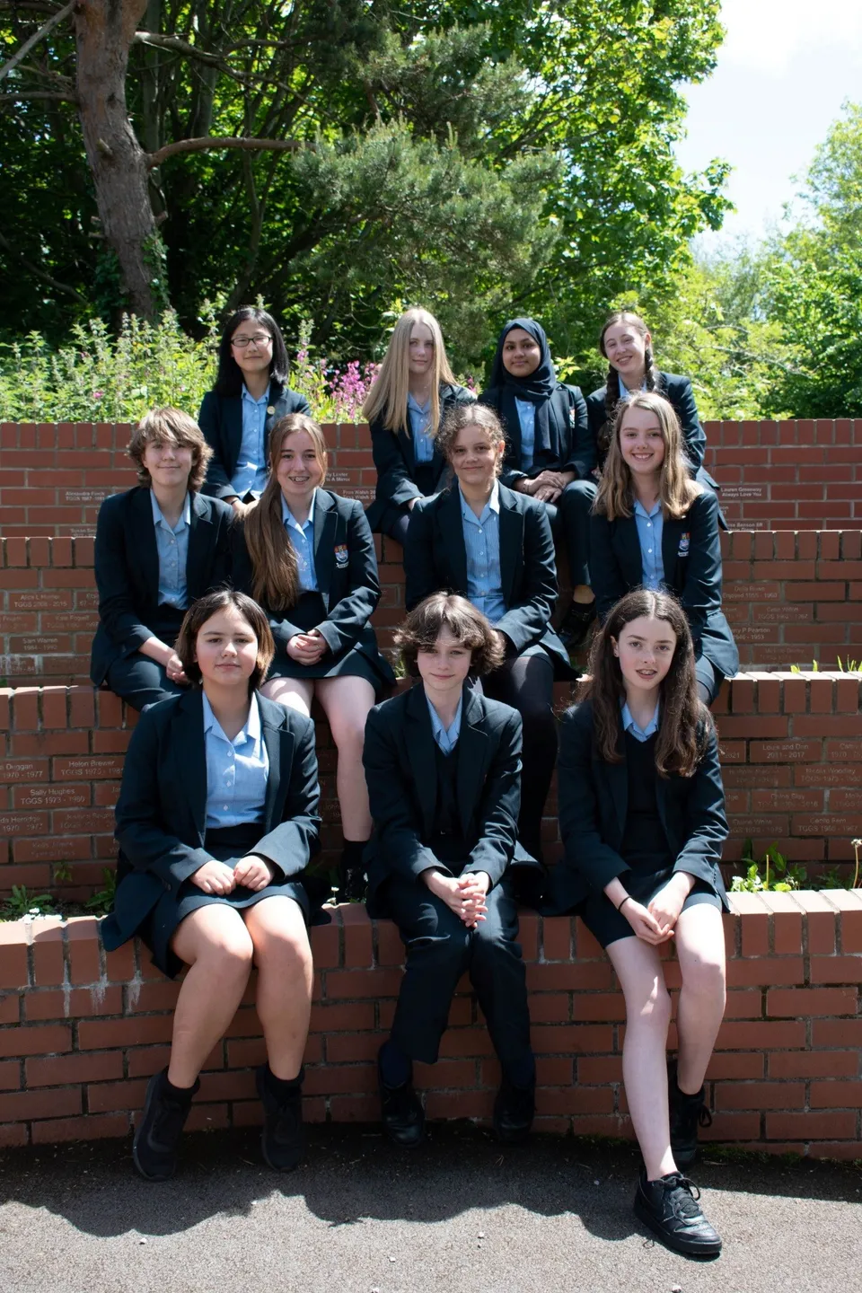 Un gruppo di studentesse della Torquay Girls Grammar School in piedi insieme davanti a un muro di mattoni.